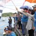 Bupati Luwu Timur, Irwan Bachri Syam dan Wabup Lutim, Puspwati mengangkat bendera start tanda dimulainya Lomba Perahu bala-Bala di Anjungan Sungai Malili. (Foto: Kominfo SP Lutim)