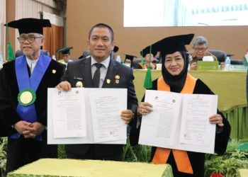 Bupati Luwu Timur, Irwan Bachri Syam bersama Ketua Yayasan Wakaf UMI, Masrurah Mokhtar, memperlihatkan MoU di hadapan civitas akademika dalam Milad UMI ke-71 (Foto: Dinas Kominfo SP Luwu Timur)