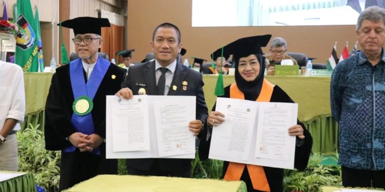 Bupati Luwu Timur, Irwan Bachri Syam bersama Ketua Yayasan Wakaf UMI, Masrurah Mokhtar, memperlihatkan MoU di hadapan civitas akademika dalam Milad UMI ke-71 (Foto: Dinas Kominfo SP Luwu Timur)