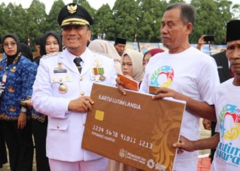 Bupati Luwu Timur, Irwan Bachri Syam, menyerahkan secara simbolis Kartu Lansia kepada perwakilan warga berusia di atas 60 tahun pada peringatan HUT ke-80 RI di Lapangan Pendidikan, Malili, Minggu (17/08/2025). (Foto: Chullank_art)