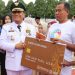 Bupati Luwu Timur, Irwan Bachri Syam, menyerahkan secara simbolis Kartu Lansia kepada perwakilan warga berusia di atas 60 tahun pada peringatan HUT ke-80 RI di Lapangan Pendidikan, Malili, Minggu (17/08/2025). (Foto: Chullank_art)