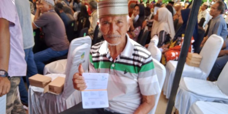 Jafar, warga Desa Atue memperlihatkan buku rekening saat pencairan perdana Kartu Lutim Lansia, di Halaman Kantor Bupati Lutim, Kamis (30/10/2025). Foto: Jaeja.id