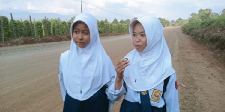 Dua pelajar menyampaikan apresiasi atas perhatian Pemkab Luwu Timur membenahi jalan Mahalona Raya. Foto: Warta Lutim