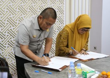 Bupati Luwu Timur, Irwan Bachri Syam dan Dirut PT Intim Technologia Sejahtera, Rianawati, menandatangani MoU stasiun pengisian kendaraan listrik di ruang kerja bupati, Sabtu (18/04/2026).