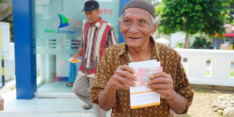 Seorang lansia di Kacamatan Burau baru saja menarik uang di ATM menggunakan Kartu Lansia Luwu Timur, Jumat (24/07/2028). Foto: Warta Lutim
